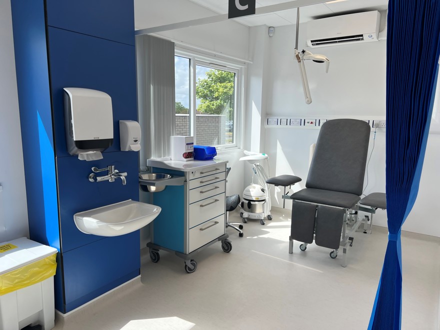 A photograph of a new plaster room bay, with a grey seat, white and mid-blue walls and a sink.